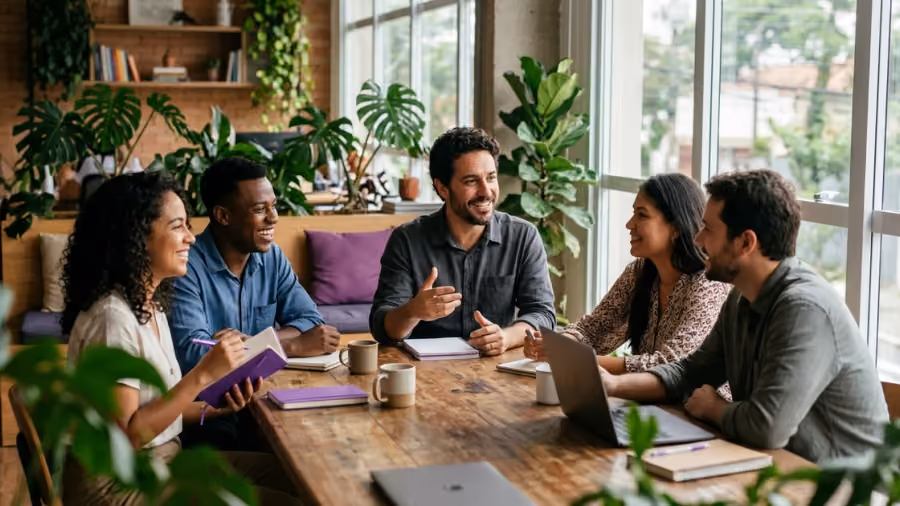 Fundador de uma pequena empresa conversando com a equipe em volta de uma mesa