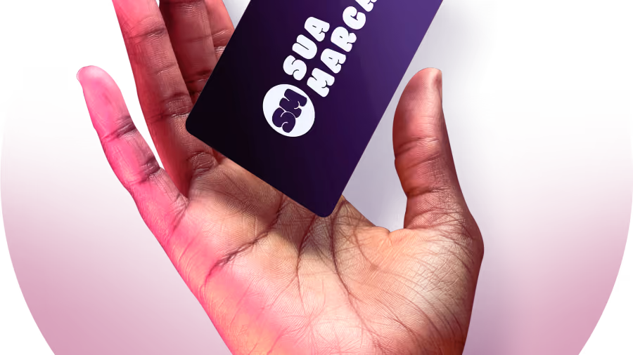 Foto de mão aberta segurando um cartão roxo escuro com a inscrição sua marca e um logotipo genérico, sobre fundo rosa